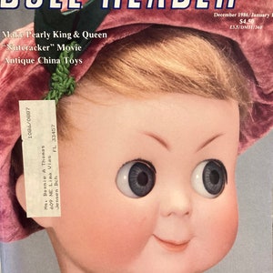 May include: A vintage magazine cover featuring a doll with large blue eyes and a pink hat. The magazine is called "Doll Reader" and the cover text says "Make Pearly King & Queen, "Nutcracker" Movie, Antique China Toys".