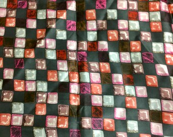 May include: A black fabric with a repeating pattern of colorful squares. The squares are in shades of pink, red, brown, and white.