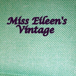 Może przedstawiać: Zielone, tekstylne tło o fakturowanej powierzchni z napisem "Miss Eileen's Vintage" w ciemnofioletowym kolorze.