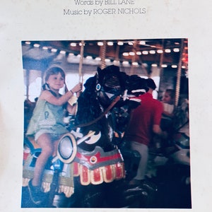 May include: Album cover for "Times Of Your Life" featuring a carousel scene. The image shows a young person riding a black carousel horse. The text includes the song title, the names of the lyricist and composer, and the recording artist.