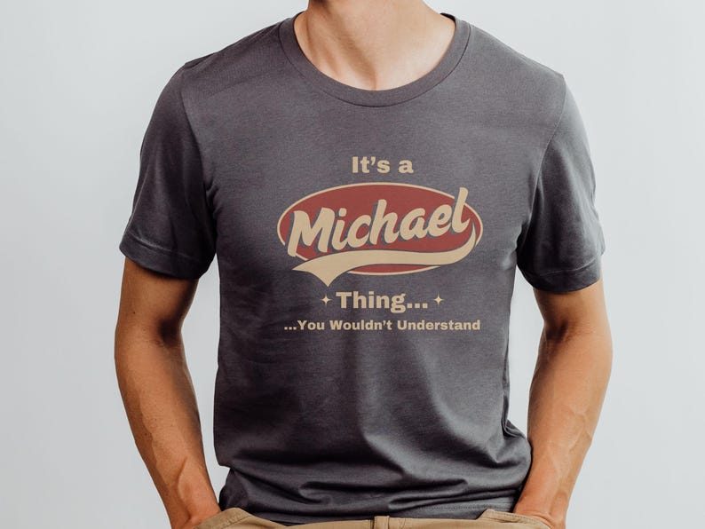 May include: A dark gray t-shirt with a red and beige graphic that says "It's a Michael Thing... You Wouldn't Understand."