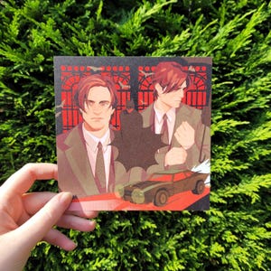 May include: A square art print featuring a stylised illustration of a man with brown hair wearing a suit and tie, positioned in front of a red gate. A dark silhouette of a caped figure and a dark-coloured muscle car are depicted in the foreground.