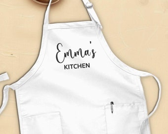 May include: White kitchen apron with a large pocket and a black text that says "Emma's Kitchen".