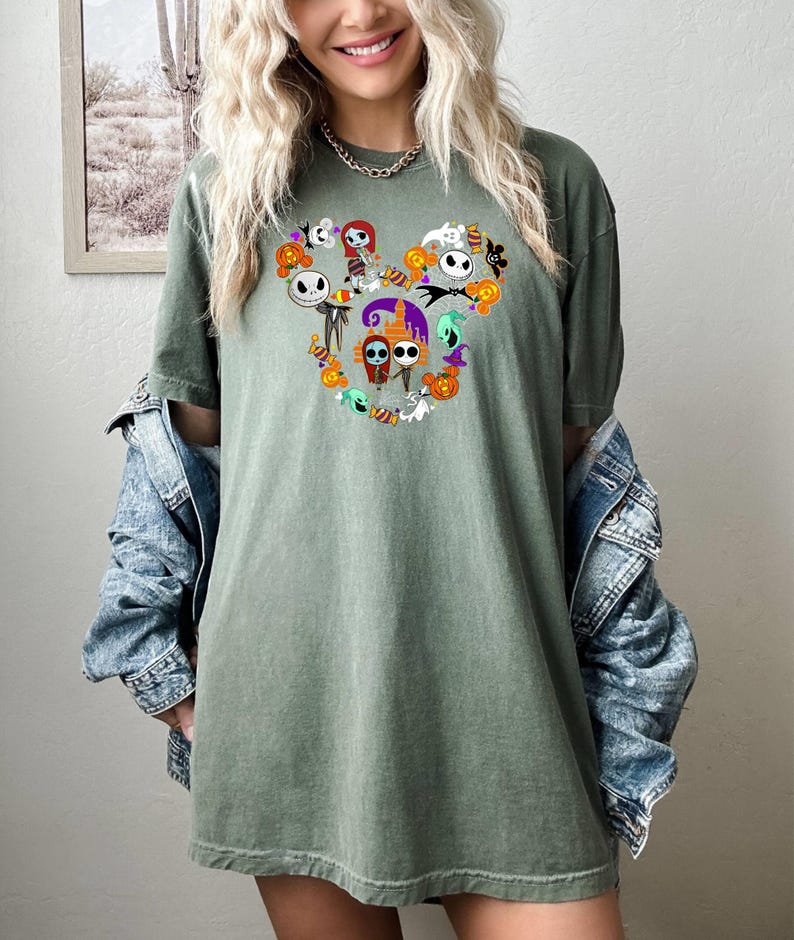 May include: A green t-shirt with a Mickey Mouse silhouette made up of characters from the Nightmare Before Christmas. The characters include Jack Skellington, Sally, Oogie Boogie, and Zero.