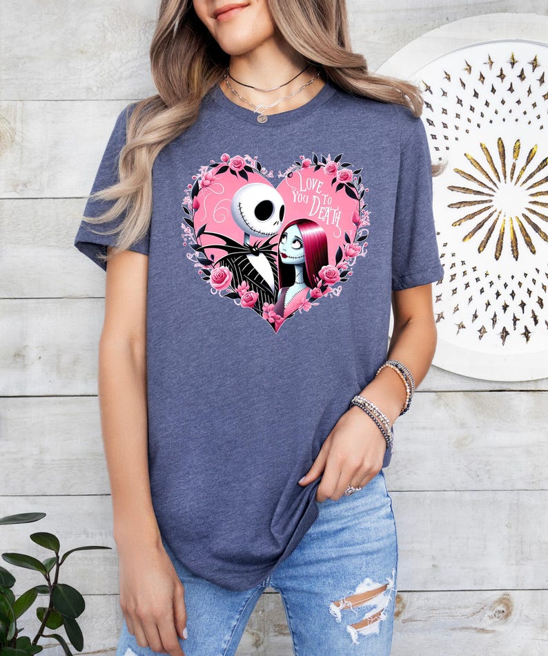May include: A navy blue t-shirt with a pink heart graphic featuring Jack Skellington and Sally from The Nightmare Before Christmas. The text inside the heart reads "Love You To Death."