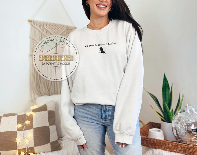 May include: White sweatshirt with the text "We do not eat our allies." and a black silhouette of a bat. The sweatshirt is embroidered with the text "Personalized Gift Embroidered Sweatshirt & Hoodie".