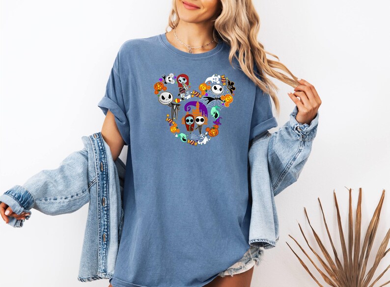 May include: A blue t-shirt with a graphic of various characters from the Nightmare Before Christmas movie, arranged in the shape of Mickey Mouse ears.