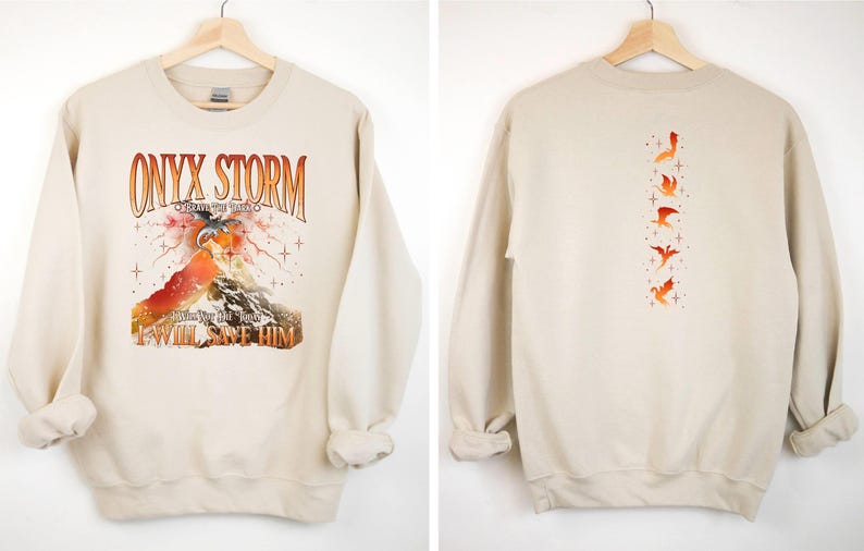 May include: A beige sweatshirt with a graphic print of a mountain, a dragon, and the text "ONYX STORM CREATIVE THE FUTURE I WILL SAVE HIM". The back of the sweatshirt has a vertical row of five dragon silhouettes.