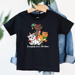May include: Black t-shirt with a graphic of three cats dressed as Christmas characters. The text "Everybody Loves Christmas" is printed below the graphic.