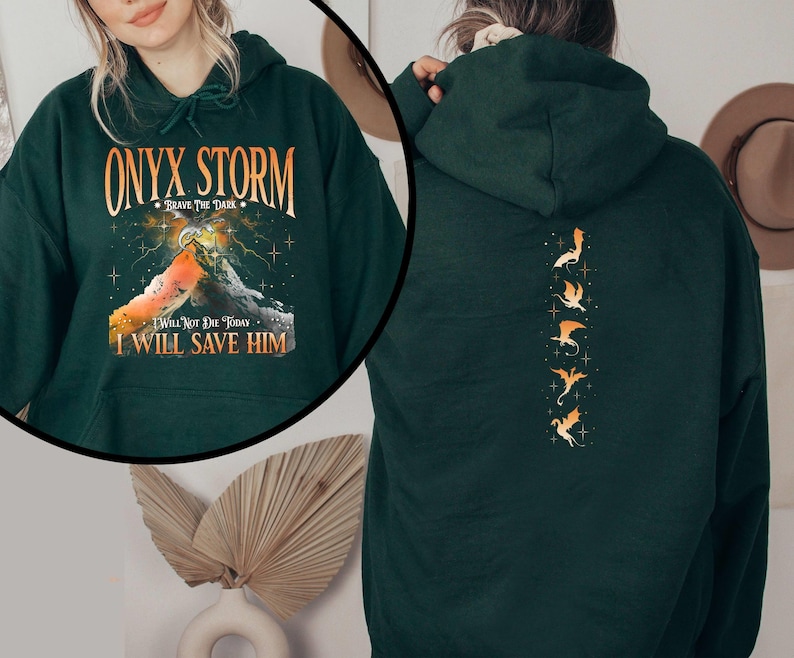 May include: A dark green hoodie with a graphic print of a mountain and the text "ONYX STORM - BRAVE THE DARK - I WILL NOT DIE TODAY - I WILL SAVE HIM". The back of the hoodie has a vertical row of five gold dragon silhouettes.