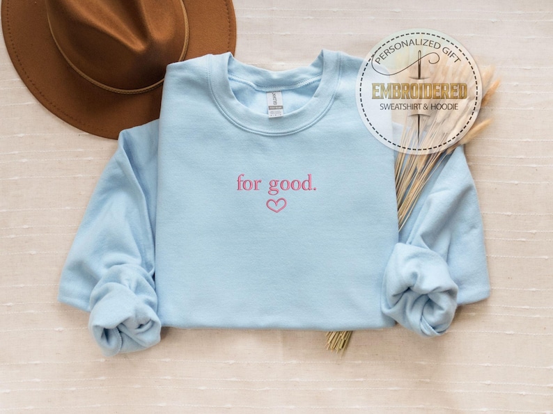 May include: Light blue sweatshirt with the text "for good." embroidered in pink with a small pink heart below the text.