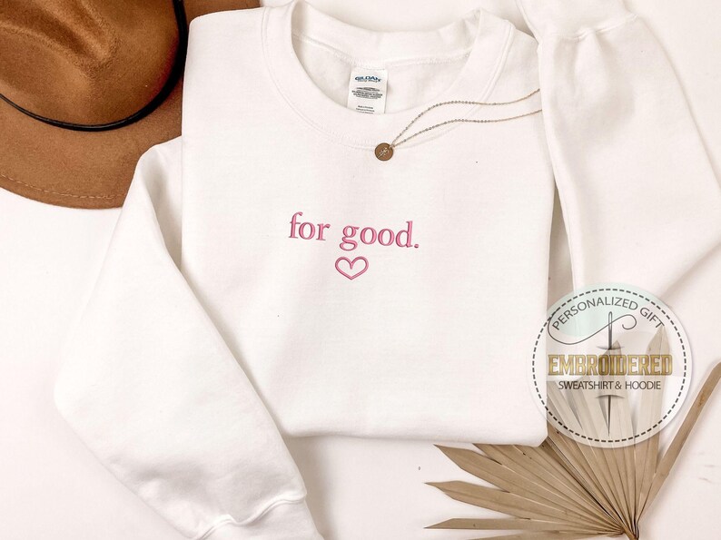 May include: White sweatshirt with the text "for good." embroidered in pink with a pink heart below the text.