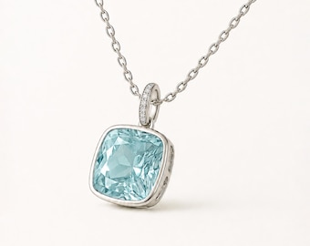 Può includere: Una collana con pendente color argento caratterizzata da una gemma azzurra a taglio quadrato con bordi sfaccettati. Il pendente è sospeso a una sottile catenina argentata e include una piccola contromaglia decorata con pietre luminose.