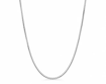 Può includere: Una collana a catena snake color argento caratterizzata da un design liscio, flessibile e continuo di maglie metalliche intrecciate. La catena presenta una superficie lucida e riflettente che cattura la luce, creando un aspetto elegante e uniforme.