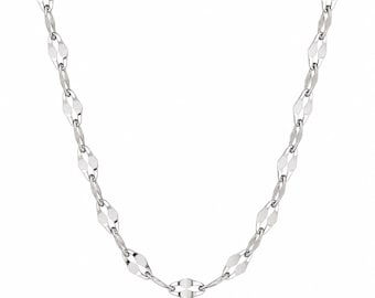Può includere: Una collana a catena color argento caratterizzata da una serie di maglie allungate a forma di diamante sfaccettato, collegate da piccoli anelli circolari. La superficie metallica ha una finitura lucida che riflette la luce.