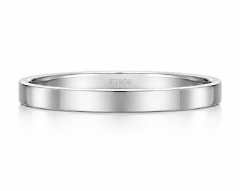 Può includere: Un anello in metallo color argento lucido con una fascia piatta e liscia. L'interno della fascia è chiaramente inciso con il testo PT950, che indica la composizione in platino di questo semplice gioiello circolare progettato per il dito.