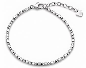 Può includere: Un bracciale color argento caratterizzato da un motivo ripetuto di piccole perline rotonde e perline cilindriche. Il bracciale include una chiusura a moschettone, una catenella di estensione regolabile e un piccolo ciondolo a cuore.