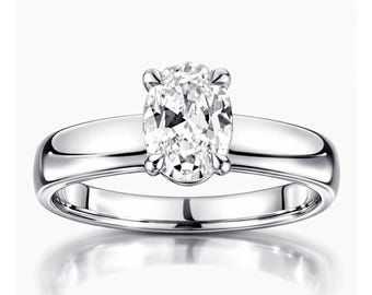 Può includere: Un anello in metallo color argento lucido con una singola pietra preziosa trasparente dal taglio ovale, fissata in una montatura a quattro griffe. La fascia è liscia e solida, con una superficie riflettente che cattura la luce.