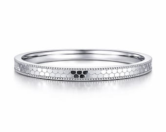May include: A silver ring with a honeycomb pattern band. The ring has a thin, polished band with a detailed design of small, connected hexagons. The edges are lined with tiny, evenly spaced dots, adding a delicate touch to the jewelry.