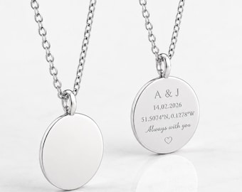 Può includere: Due collane con ciondoli circolari color argento su catenine sottili. Un ciondolo è vuoto, mentre l'altro presenta l'incisione: A & J, 14.02.2026, 51.5074°N, 0.1278°W, la scritta Always with you e un piccolo simbolo a forma di cuore.