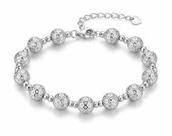 Può includere: Un bracciale color argento caratterizzato da una serie di grandi perle sferiche con una superficie testurizzata e sfaccettata. Le perle sono intervallate da perline distanziatrici rotonde e lisce. Include una chiusura a moschettone e una catenella regolabile.