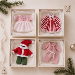 Puede incluir: Cuatro cajas de regalo cuadradas que contienen ropa para muñecas: un vestido rosa claro con ribete de encaje, un vestido a rayas rojas y blancas con encaje, una chaqueta roja con cuello blanco y pantalones verdes con gorro, y un pijama a rayas rosas y blancas.