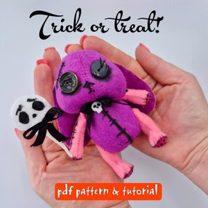 May include: A purple and pink felt Halloween doll with stitched details, black button eyes, and a black bow with a skull charm. The doll is holding a white felt ghost lollipop. The text "Trick or Treat!" is written above the doll. The text "pdf pattern & tutorial" is written below the doll.