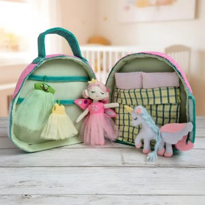Pu&ograve; includere: Uno zaino per casa delle bambole in tessuto rosa e verde, aperto per rivelare una bambola fatata, un unicorno e un letto. Lo zaino ha un manico e un motivo a pois rosa. All'interno ci sono due vestiti.