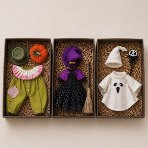 May include: Three boxed Halloween costumes: a scarecrow, a witch, and a ghost. The scarecrow costume includes green pants, a hat, and a pumpkin. The witch costume features a purple hat, black dress, and a broom. The ghost costume has a white sheet and a wand.