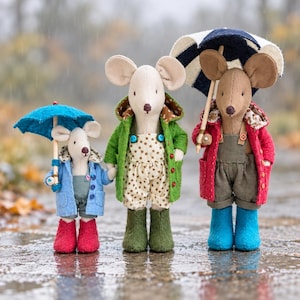 May include: Three stuffed mouse dolls standing together. The smallest wears a blue coat, grey overalls, and red boots, holding a blue umbrella. The middle mouse wears a green coat, star-print overalls, and green boots. The largest wears a red coat, olive overalls, and blue boots, holding a navy and white umbrella.