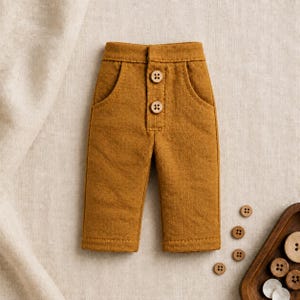 May include: Mustard yellow pants featuring a high-waisted design with two front pockets and a vertical row of three round wooden buttons centered at the waist. The pants have a straight-leg cut and a visible textured fabric finish throughout the garment.
