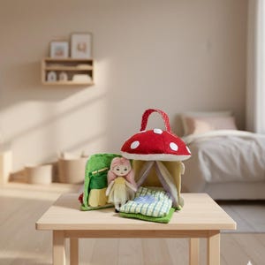 May include: A whimsical felt mushroom house with a red cap and white spots, a green felt bag, and a doll with pink hair and a yellow dress. The set includes a small bed with a green and white checkered blanket.