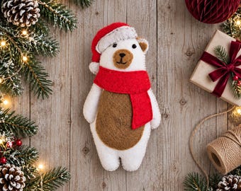 May include: A felt polar bear ornament featuring a white body with a brown belly, wearing a red scarf and a red Santa hat with a white trim. The bear has black bead eyes and a stitched brown nose, presented as a festive holiday decoration.