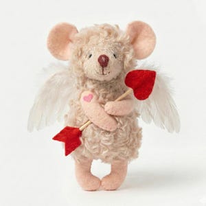 Puede incluir: Un peluche de ratón con grandes orejas rosas, sosteniendo una flecha roja en forma de corazón. El ratón tiene alas de plumas blancas y un pequeño corazón rosa en el brazo. El juguete es beige, ideal para el Día de San Valentín.
