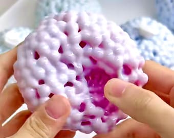 Op de afbeelding: Een witte en roze squishy bal met een textuur. De bal is gemaakt van kleine, ronde kralen die aan elkaar zijn verbonden. De binnenkant van de bal is felroze.