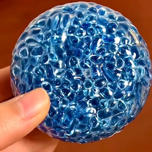 May include: A blue squishy ball with a textured surface made of many small bubbles.