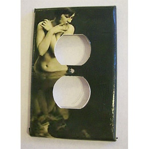 May include: A black and green outlet cover with a vintage image of a woman in a flowing dress.