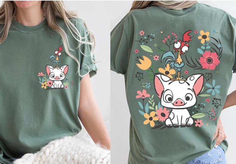 May include: Green t-shirt featuring a cartoon pig and rooster design with floral accents. The front of the shirt shows the pig and rooster with flowers. The back of the shirt has a larger version of the design.