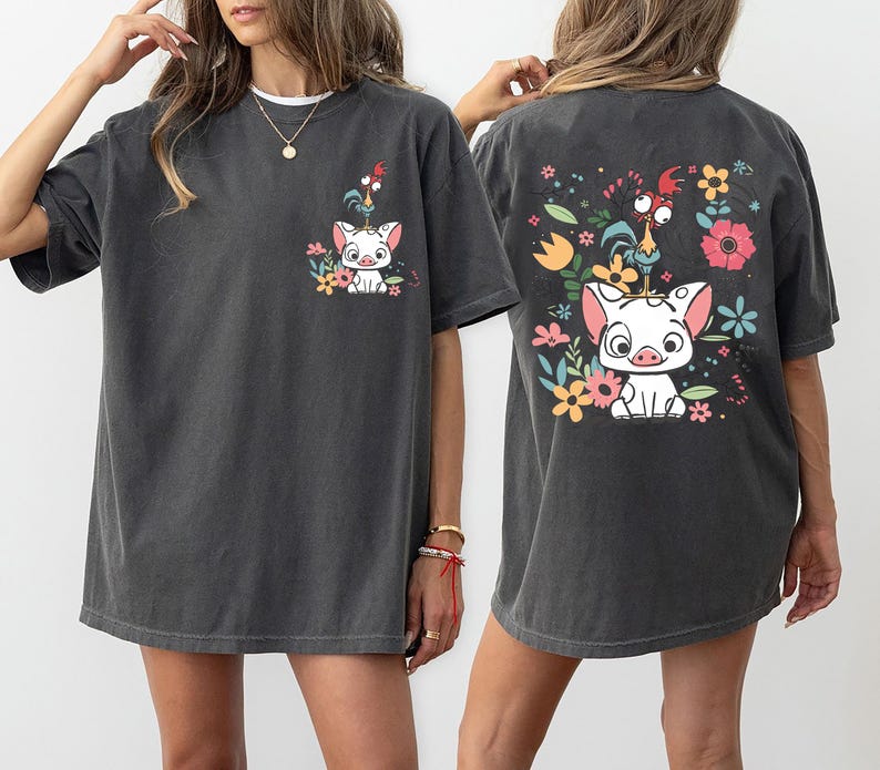 May include: Dark gray t-shirts with a cartoon pig and rooster design. The front of the shirt has a small graphic, while the back features a larger version with colorful flowers.