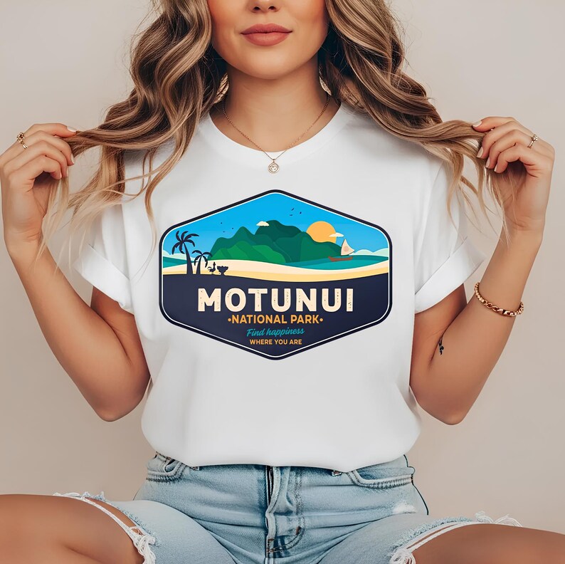 May include: White t-shirt with a graphic of a coastal scene, including the text "MOTUNUI NATIONAL PARK". The design features palm trees, a sailboat, and mountains under a blue sky and setting sun. The text "Find happiness where you are" is also included.