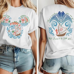 May include: White t-shirt featuring a colorful design with the text "THAT WAY I KNOW THE WAY" in a Mickey Mouse head shape. The back of the shirt has a boat design with the text "There is nowhere you can go that I won't be with you..."