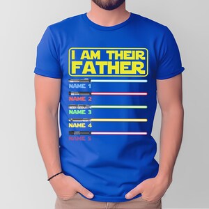 May include: Blue t-shirt with the text "I AM THEIR FATHER" in yellow. Below the text are five lightsaber designs with space for names. The lightsabers have different colored blades: blue, red, green, yellow, and pink.