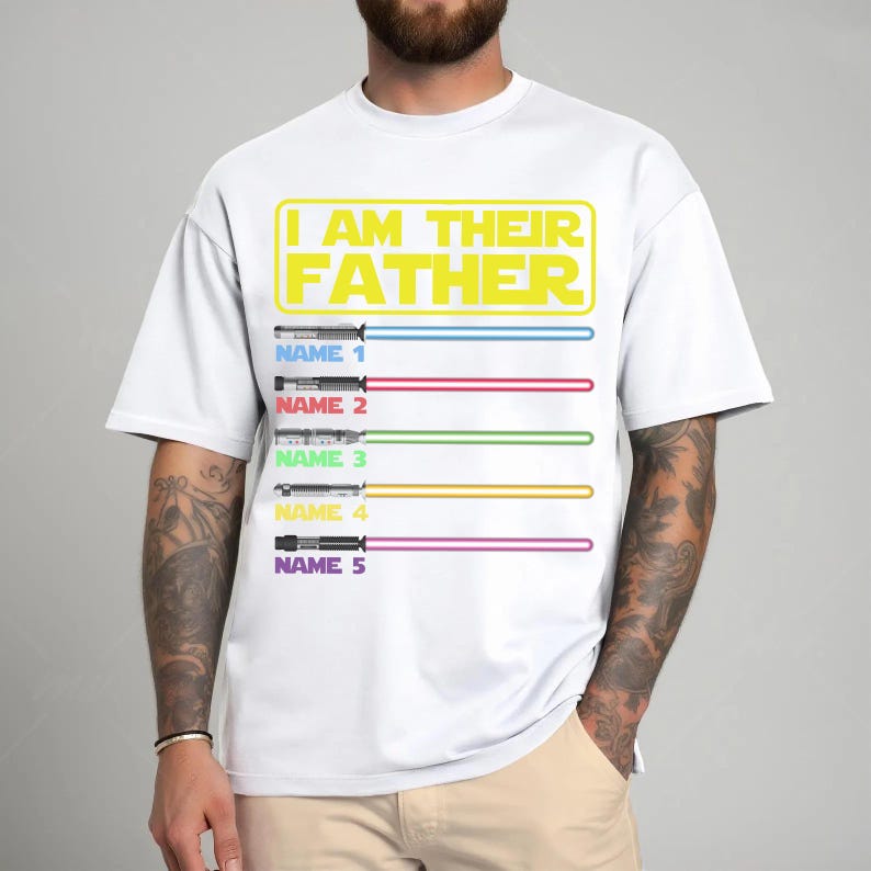May include: White t-shirt with the text "I AM THEIR FATHER" in yellow. Below the text are five lightsabers with different colors and the option to add names. A fun, personalized gift.