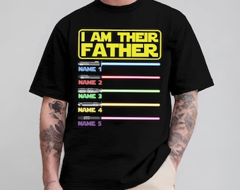 Könnte beinhalten: Schwarzes T-Shirt mit dem Text "I AM THEIR FATHER" in Gelb und Weiß. Darunter befinden sich fünf Lichtschwert-Designs mit den Namen 1 bis 5. Jedes Lichtschwert hat eine andere Farbe.