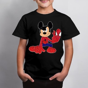 Op de afbeelding: Zwart t-shirt met een cartoon illustratie van Mickey Mouse verkleed als Spider-Man. Het personage is afgebeeld in een dynamische pose, met rode en blauwe kostuumdetails. Het ontwerp bevat een spinnenembleem op de borst.