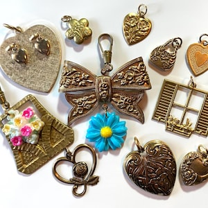 May include: A collection of 12 vintage gold-tone charms, including a heart, a bow, a window, a flower, a purse, and a flower bouquet. The charms are perfect for adding a touch of vintage style to jewelry or crafts.