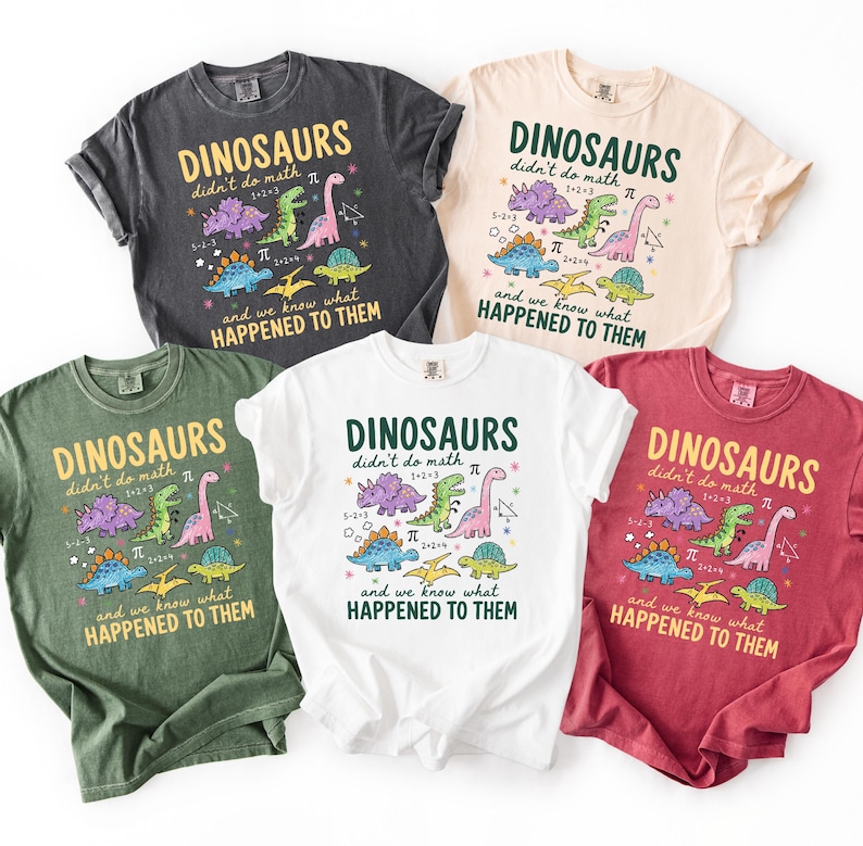 five t-shirts with dinosaur designs and text, arranged in a row.