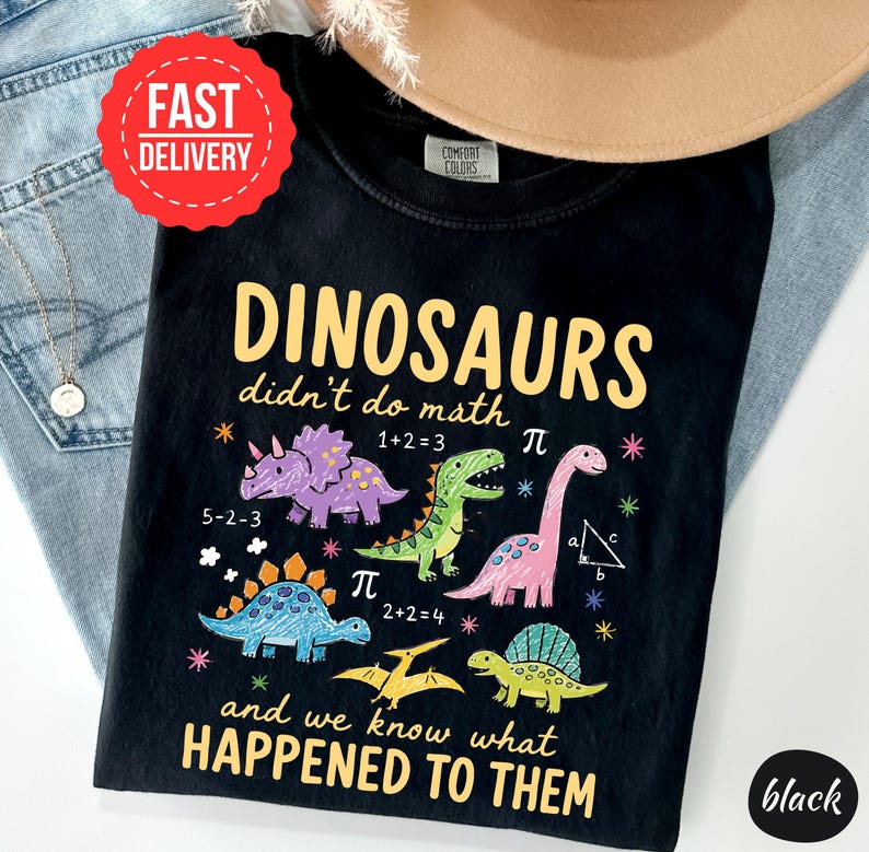 A black t-shirt with a humorous dinosaur-themed design, including a dinosaur with a math equation, and text that reads "DINOSAURS didn't do math and we know what happened to them".