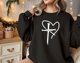May include: Black sweatshirt featuring a white heart-shaped design with a cross and a stylized letter 'I'. The long-sleeved top is made of a soft material. The design is centered on the front of the shirt.