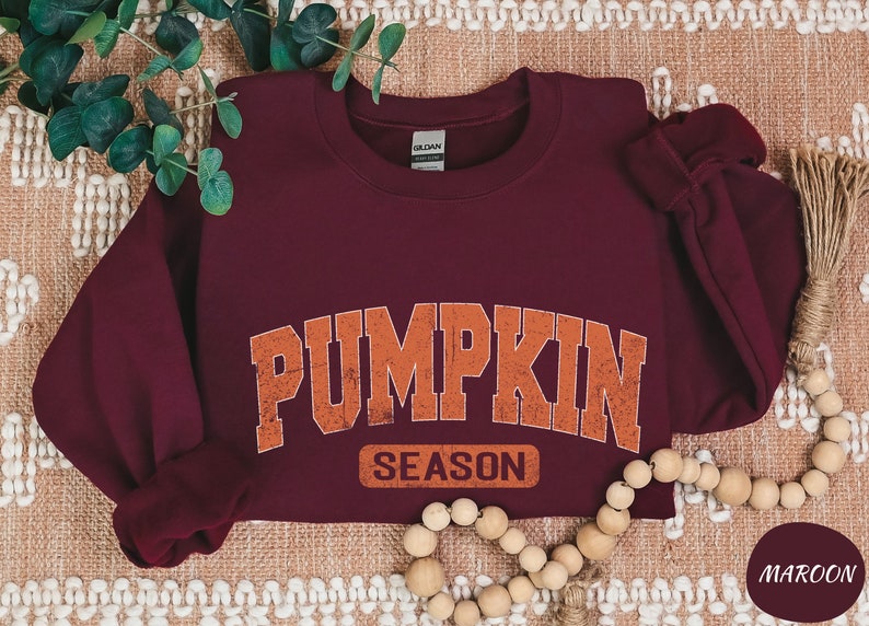 a maroon sweatshirt with a pumpkin on the front and the word pumpkin on the back